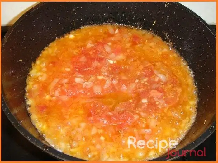 Убрать курицу со сковороды, добавить еще (если требуется) масла, мелко порезать лук, чеснок и обжарить до прозрачности лука. Затем добавить протертые консервированные помидоры и тушить примерно 5 минут.