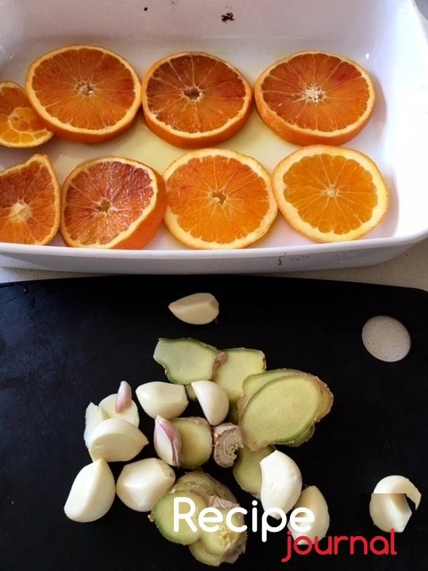 Апельсин режем кружочками и выкладываем на смазанный маслом противень. Чеснок чистим, имбирь режем как придется.