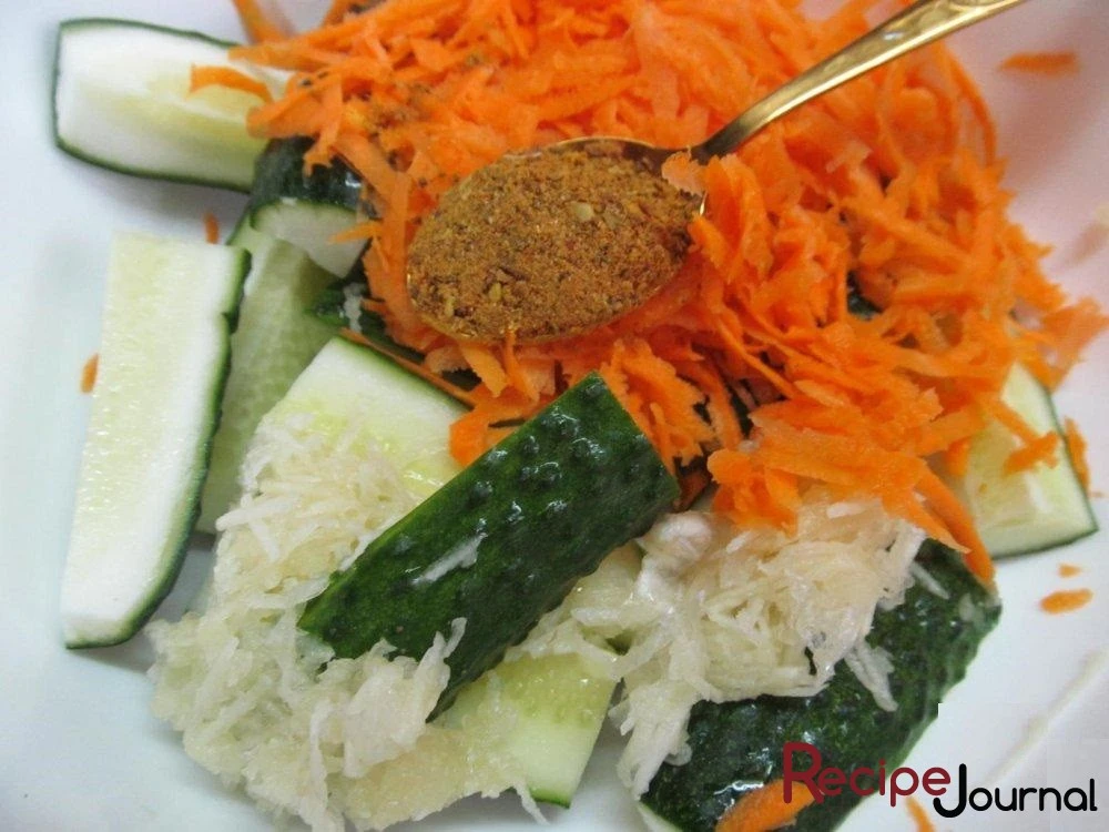 Морковь и чеснок натереть на крупной терке и добавить к огурцам, добавить приправу для моркови по-корейски.