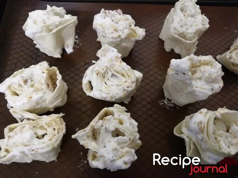 Застелить противень пекарской бумагой и разложить  порции лаваша вертикально. Отправить в разогретую до 160<sup>о</sup> духовку на 20 минут.