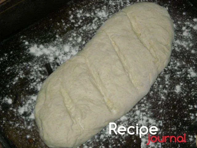 Форму для запекания смазываем растительным маслом и выкладываем подготовленный батон хлеба. Отставляем в теплое место на 40 минут для подъема. И включаем духовку на разогрев до 180<sup>о</sup>.